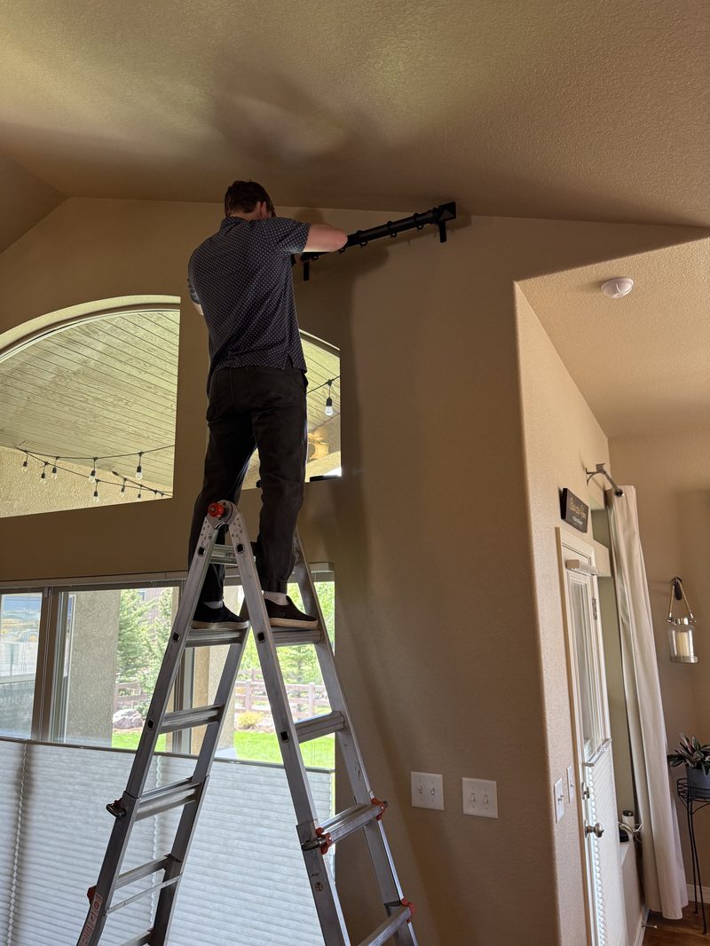 Installing a curtain rod on a two-story entry wall from an extension ladder