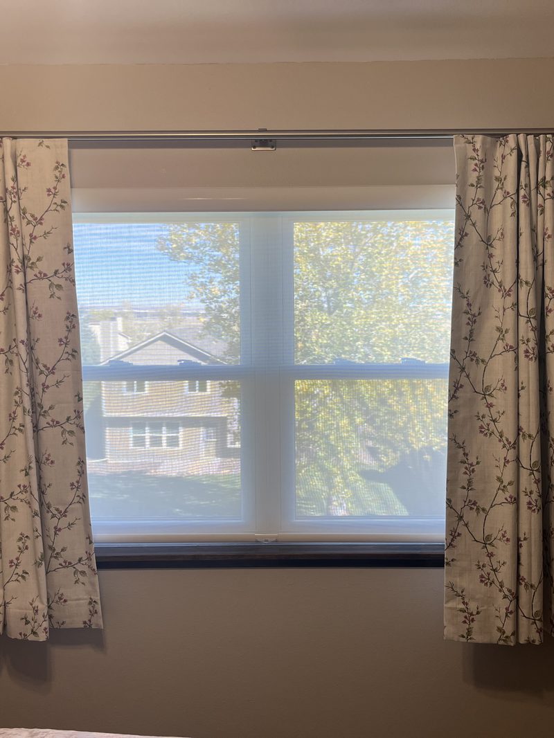 Pinch-pleat drapery hung over a bedroom window