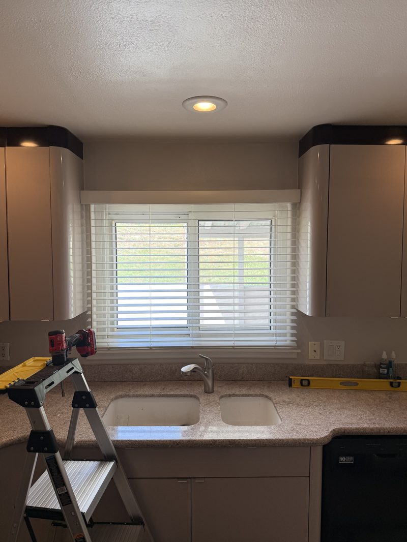 Faux wood blinds installed over a kitchen sink window