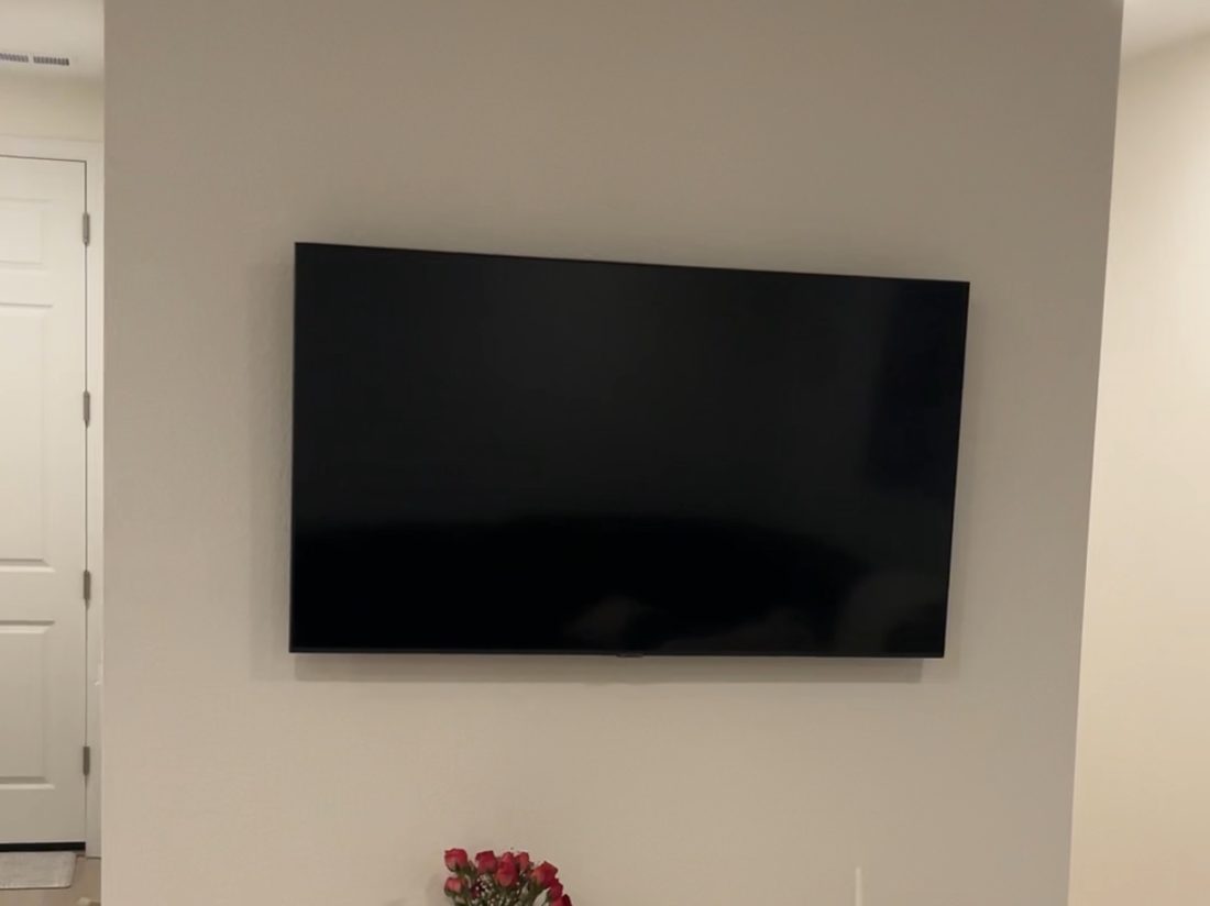 Flat screen TV mounted level on a living room wall above a console table