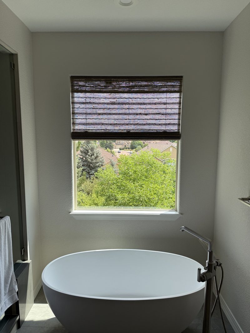 Woven wood shade installed above a freestanding bathtub